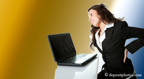 a person Vancouver bending over a computer holding her back due to pain